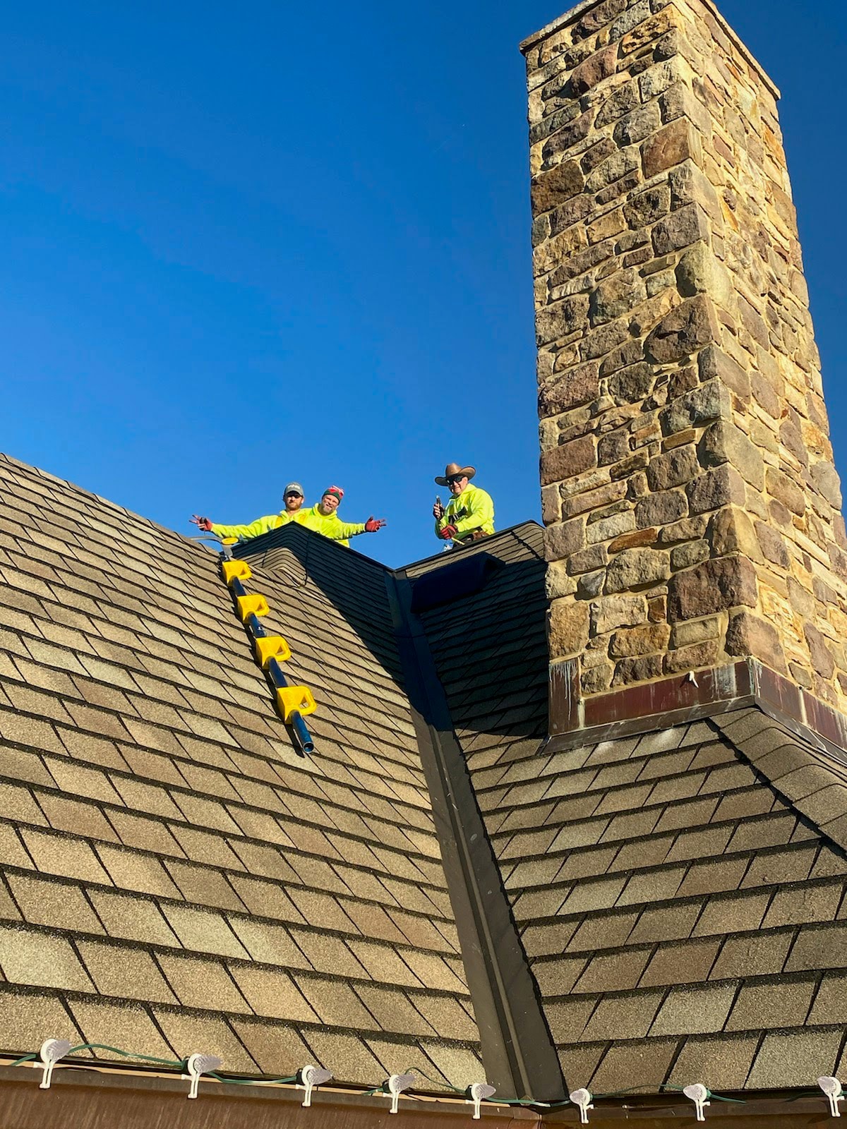 E.L.F. Designs crew on a steep shingled rooftop during a holiday lighting installation in Churchville, Maryland
