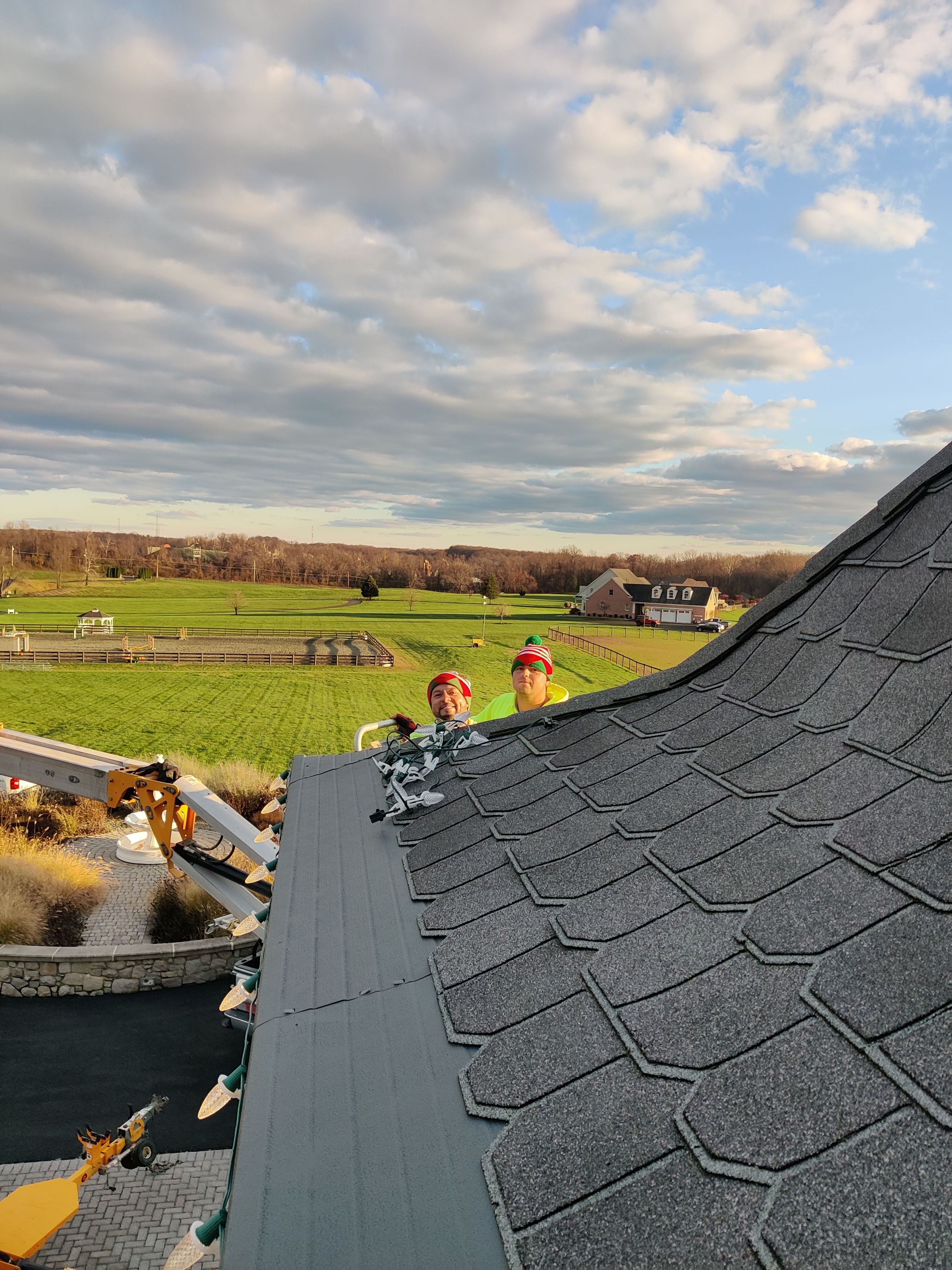 E.L.F. Designs crew peeking over a rooftop with scenic farmland views during a lighting installation in Harford County, Maryland