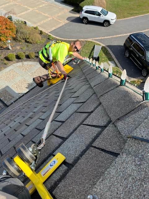 E.L.F. Designs technician in safety harness installing holiday lights on a rooftop in Forest Hill, Maryland
