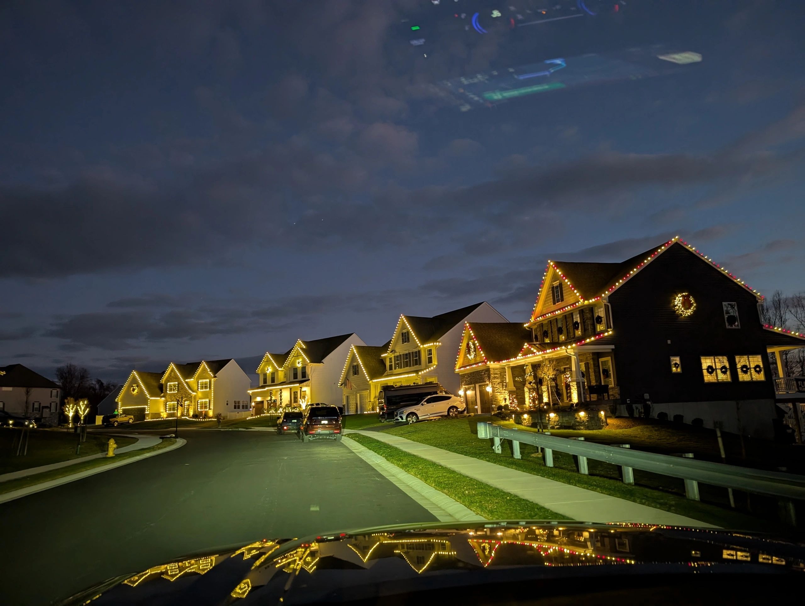 A suburban neighborhood illuminated with custom holiday lights at night.