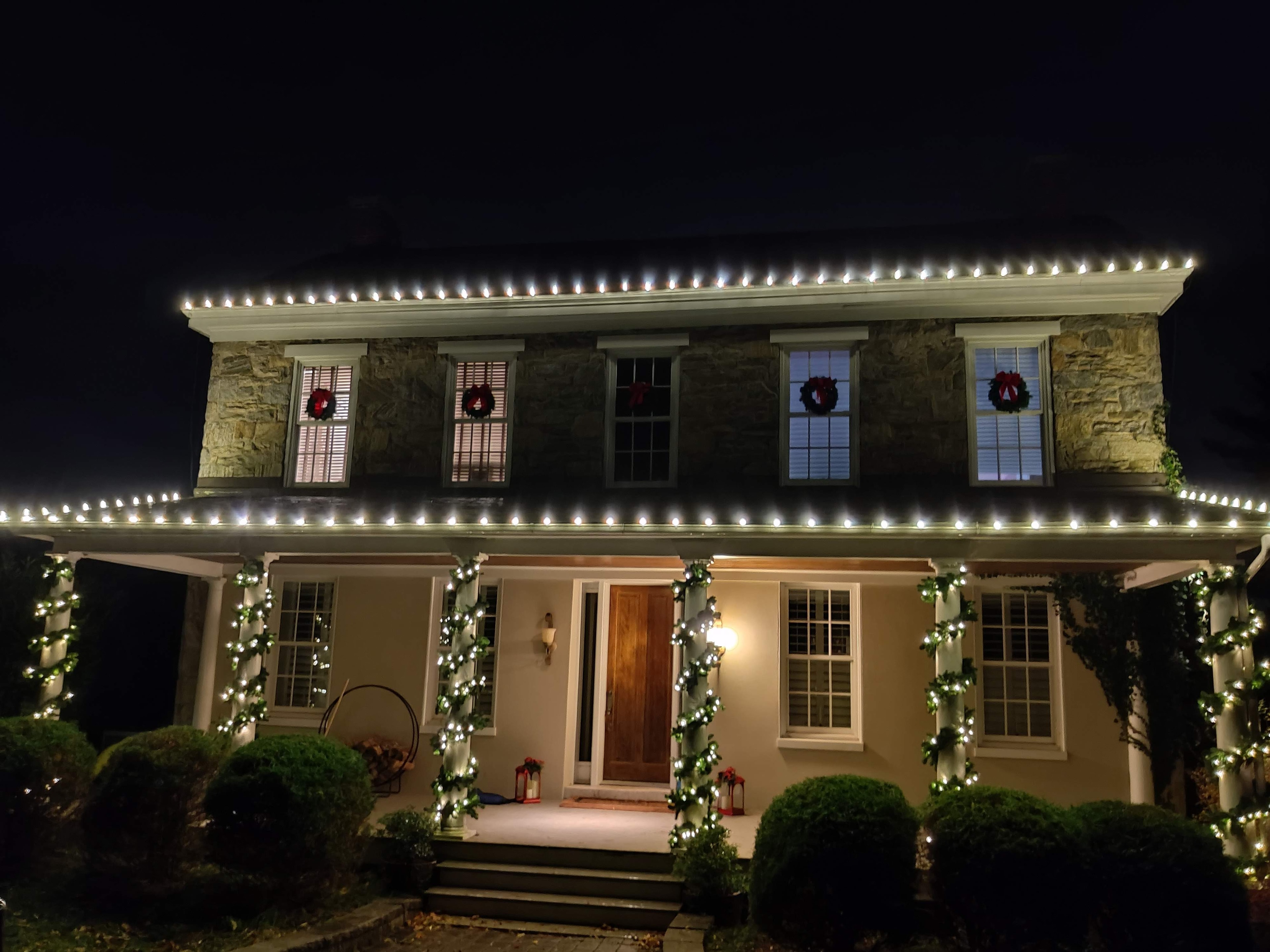 Warm white roofline lights and wrapped porch pillars illuminate home.