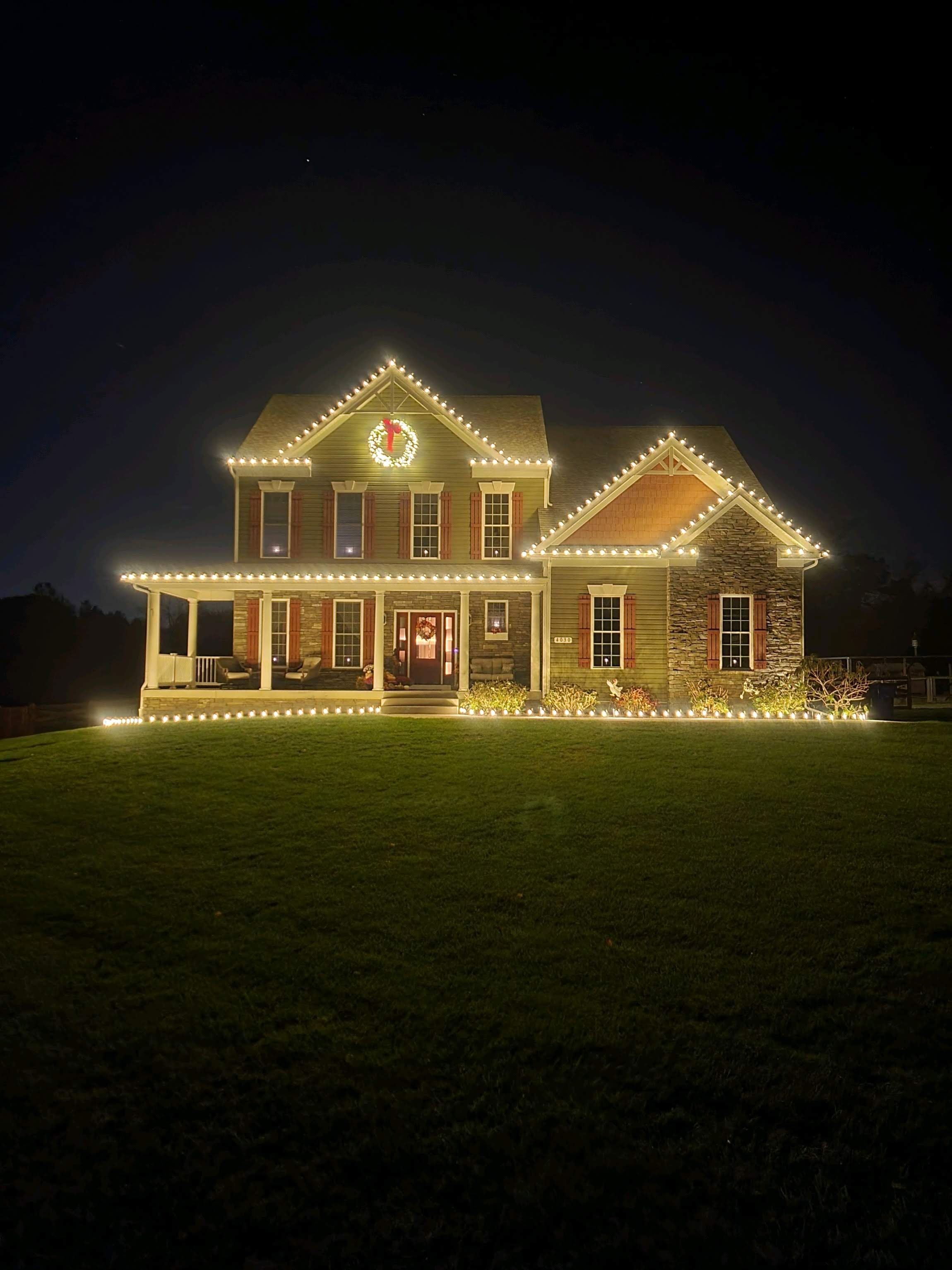 Bright warm white lights trace a two-story home's rooflines.