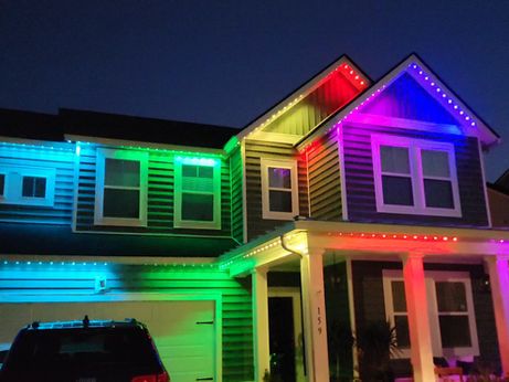Vibrant permanent lighting installed on a multi-story home exterior.